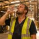 Sweating warehouse worker drinks water